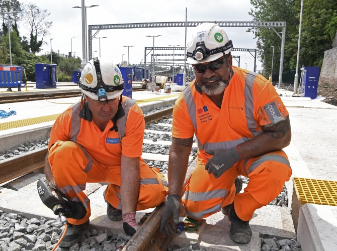 two men kneeled down on track at a depot