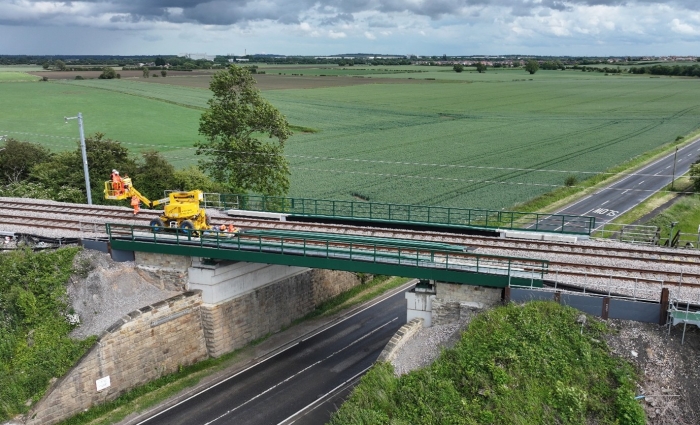 RRV on a track near a bridge surrounded by a green field