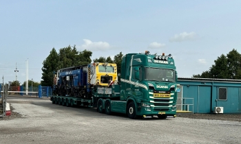 A Beaver tamper being transported on a back of a lorry