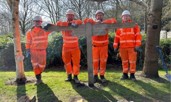 men standing next to sign in orange PPE