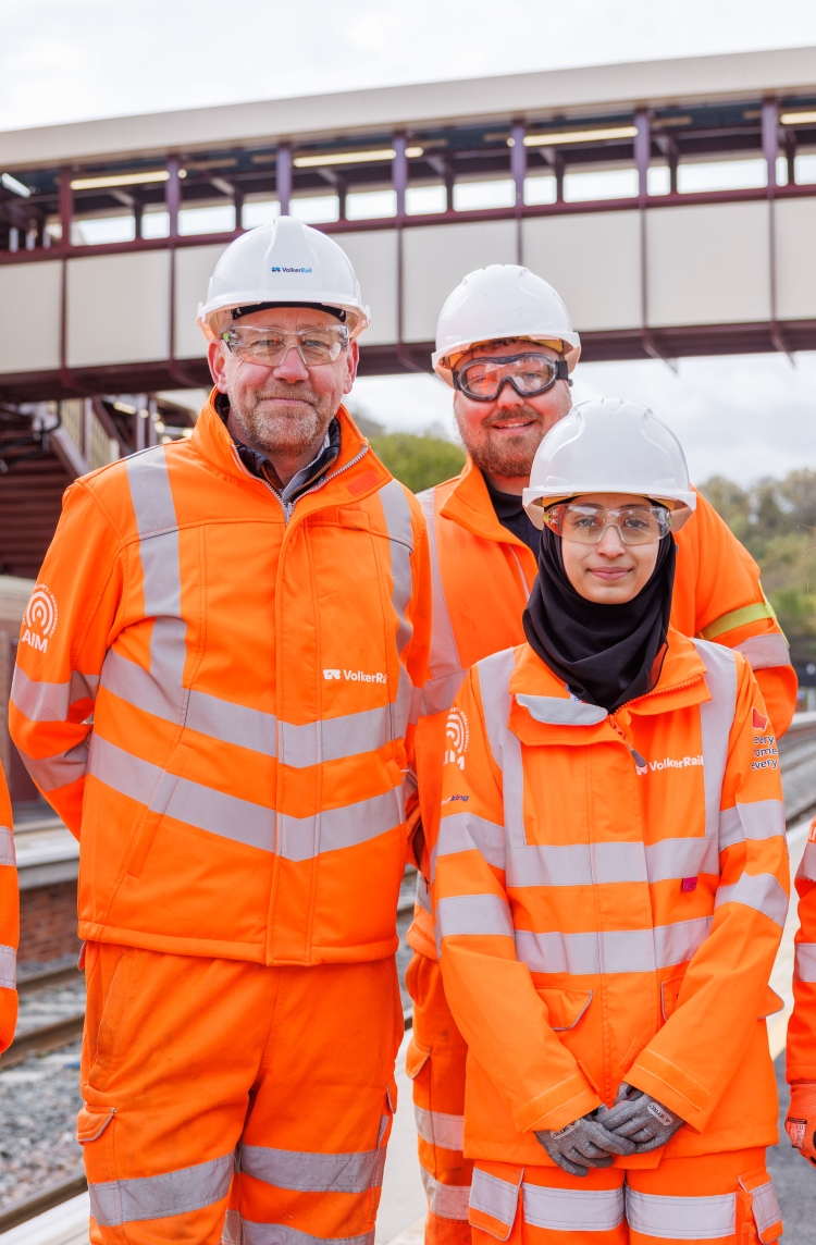 a group of smiling employees in PPE on a platform