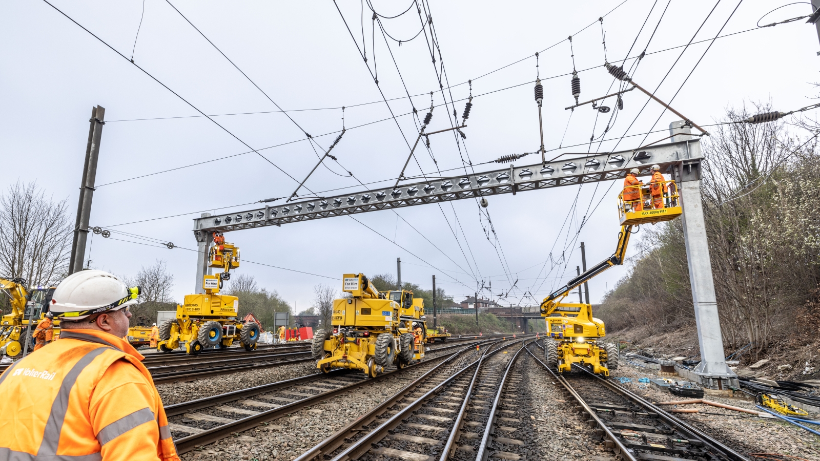 Rail operative looking up at an overhead line gantry being installed by VolkerRail using MEWPS and road rail vehicles on the Transpennine route upgrade project 