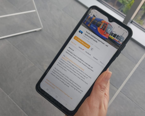 Someone holding a phone showing the community app for south Yorkshire Supertram