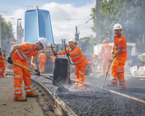 Men building a new track track in orange PPE and smiling